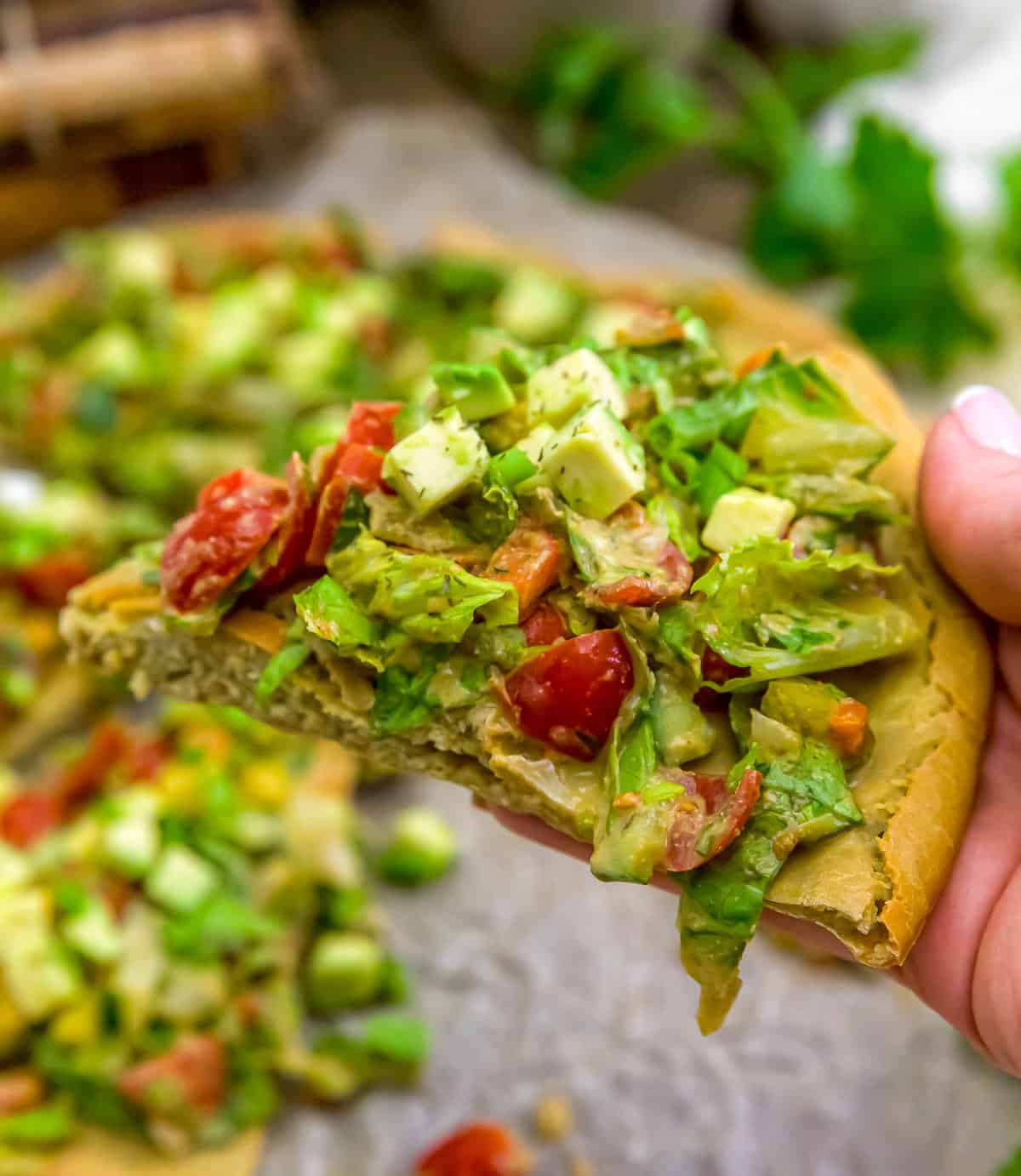 Holding a Slice of Garden Salad Flatbread Pizza